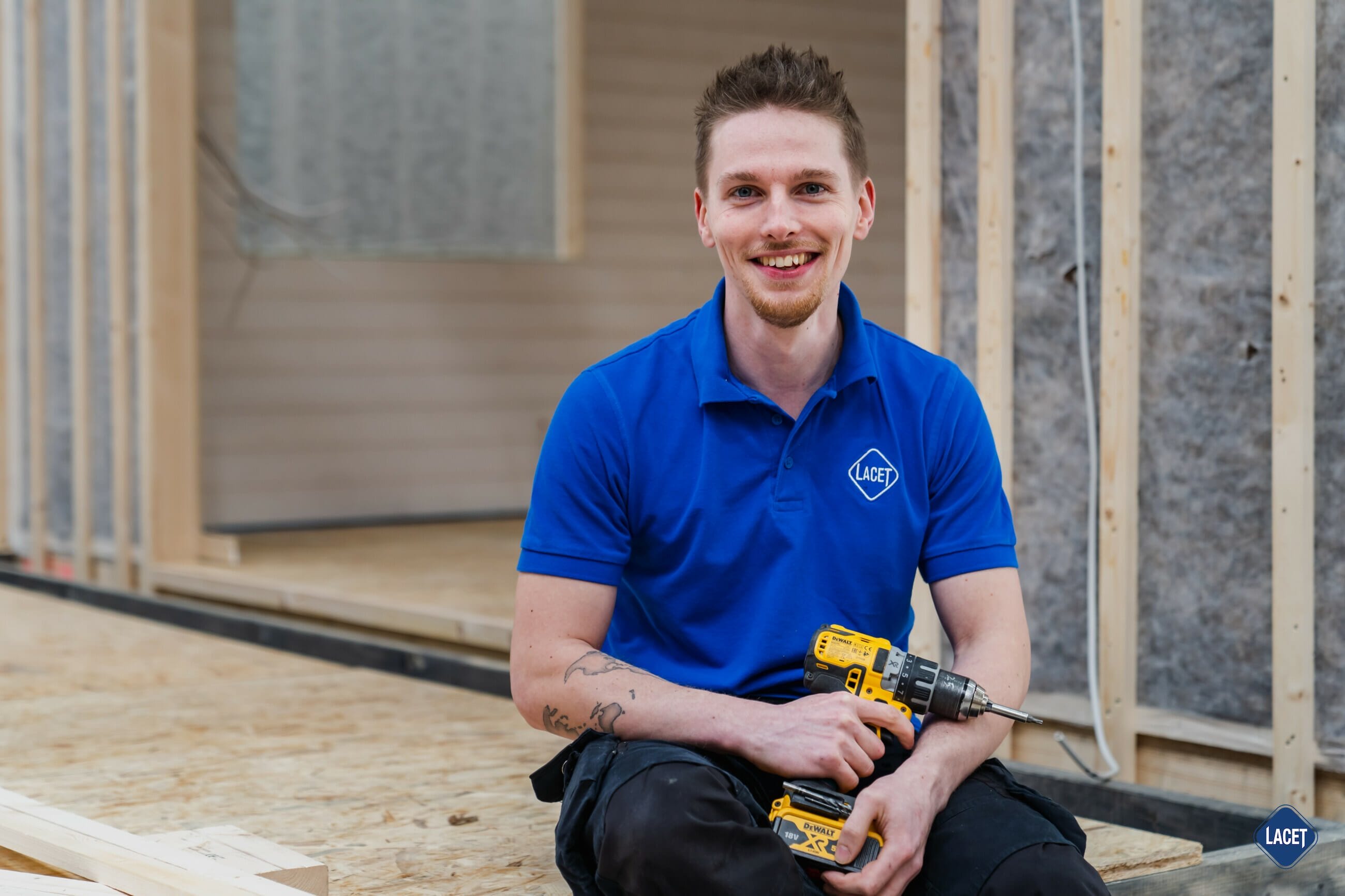 Ein Mann mit einer Bohrmaschine sitzt auf dem Boden eines Hauses.