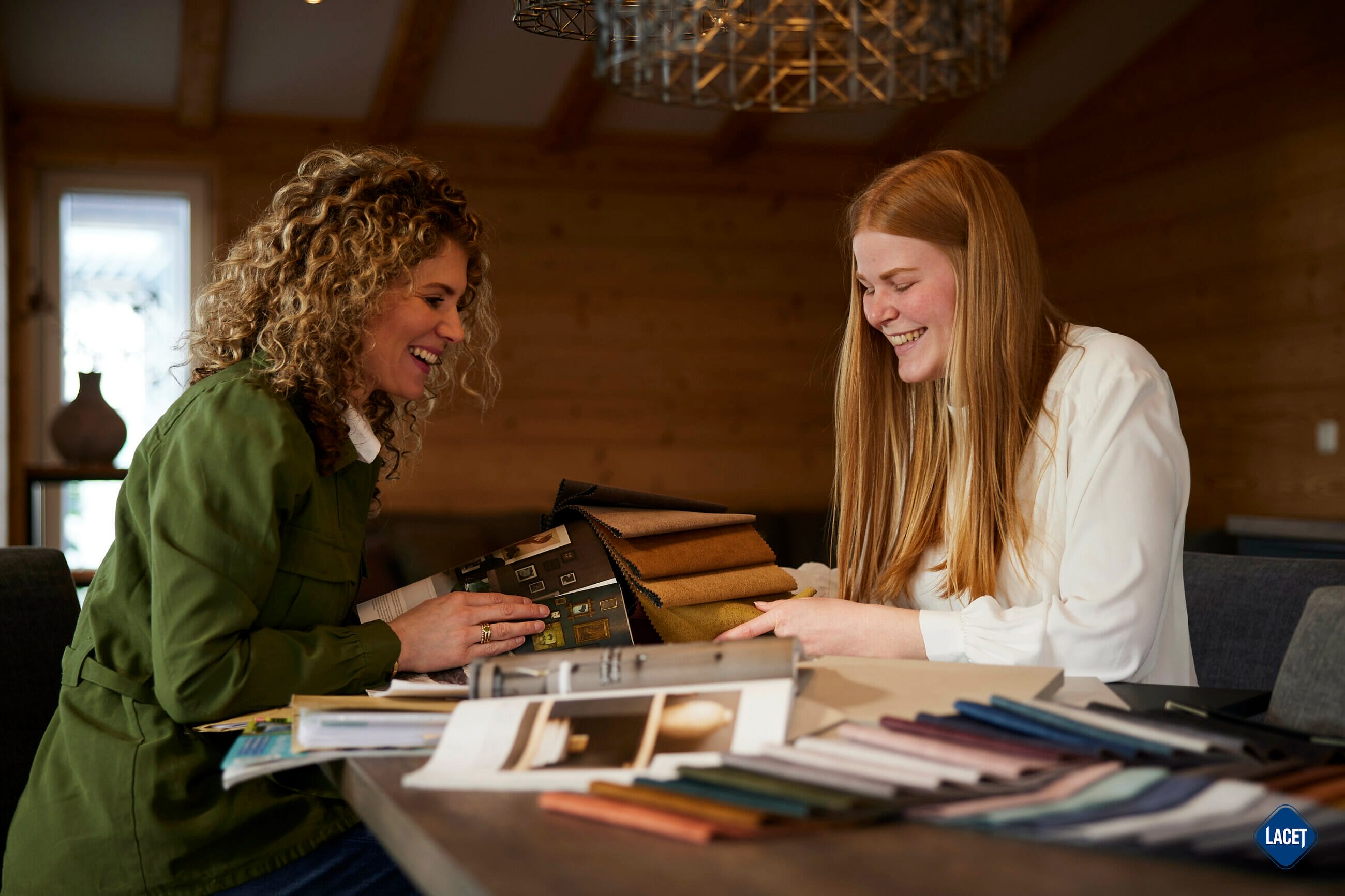 Zwei Frauen sitzen an einem Tisch und schauen sich Bücher an. LACET Niederrhein: Was uns als Arbeitgeber besonders macht